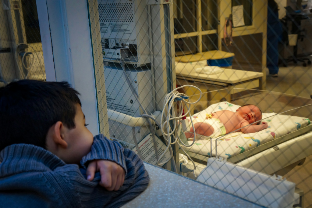 Baby with HIE being observed by their brother in the hospital.